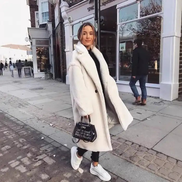 .sherpa coat in white paired with black outfit and sneakers, walking on a stylish London street.