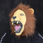 Side angle of adult lion mask with open mouth, brown mane, and yellow fangs.
