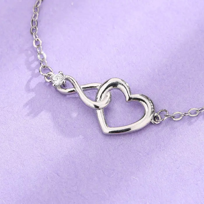 Silver heart infinity bracelet for women, featuring a sparkling gemstone on a dainty chain.