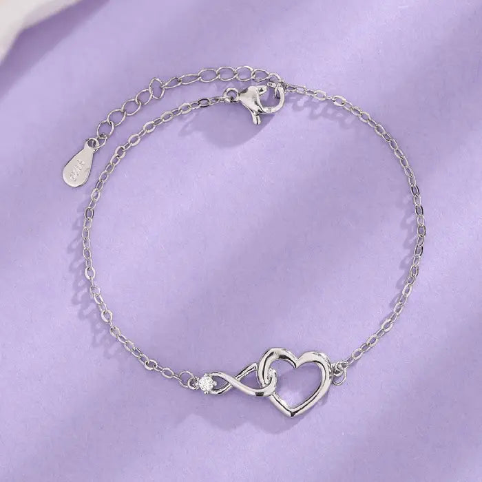 Dainty silver heart infinity bracelet with a sparkling crystal and adjustable chain clasp design.