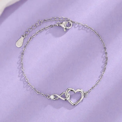 Dainty silver heart infinity bracelet with a sparkling crystal and adjustable chain clasp design.