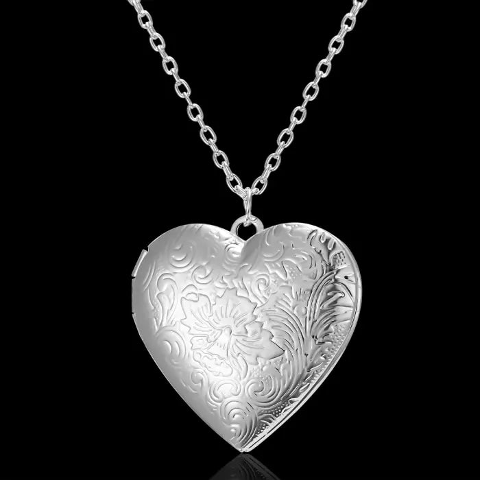 Silver heart-shaped locket with detailed floral engravings, a timeless and elegant jewelry piece.