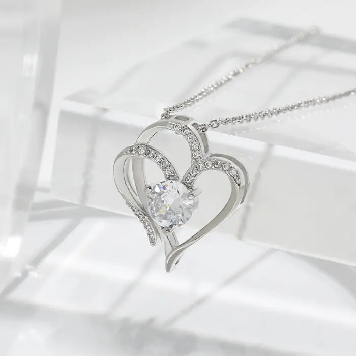 Close-up of a silver heart-shaped pendant adorned with sparkling stones, highlighting its intricate details.