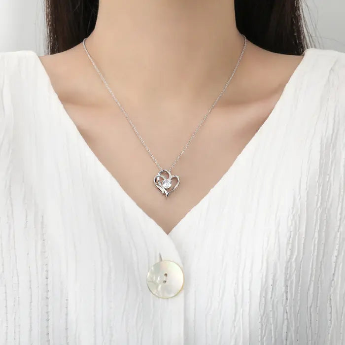 Silver heart-shaped pendant necklace worn by a model, showcasing its elegant and minimalist design.