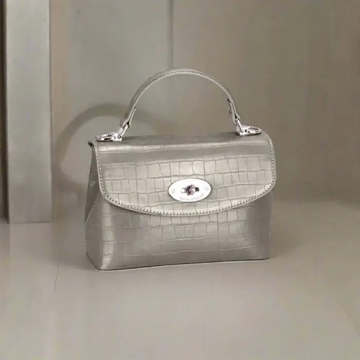 Silver crocodile-textured leather handbag with a sleek design and silver clasp for sophisticated outfits.