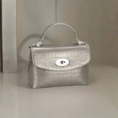 Silver crocodile-textured leather handbag with a sleek design and silver clasp for sophisticated outfits.