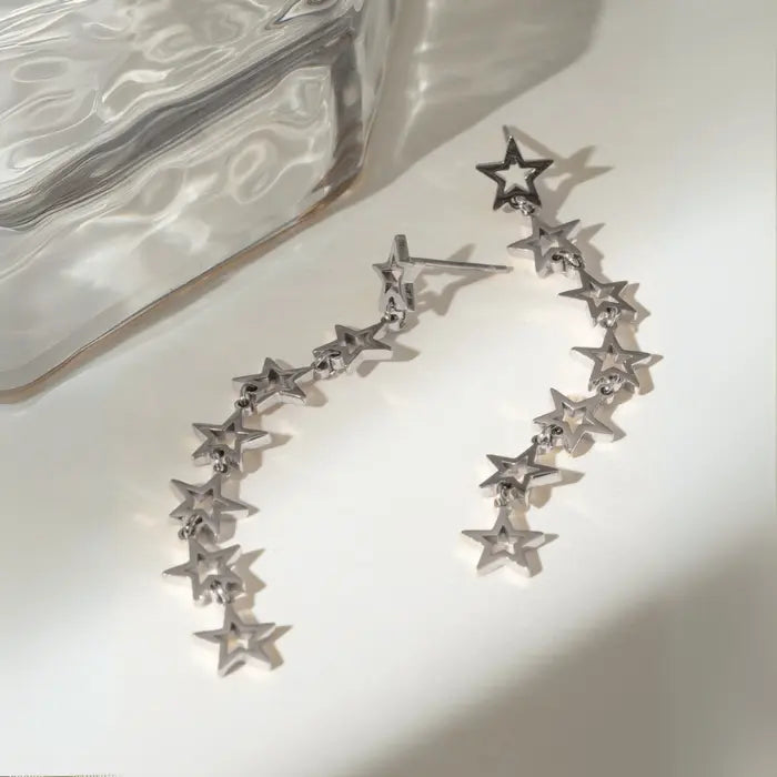 Silver star chain earrings with connected design on white surface