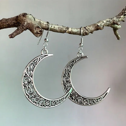 Elegant silver moon dangle earrings hanging on a branch, perfect for boho-inspired jewelry lovers.