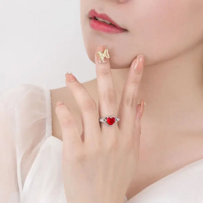 Woman displaying a silver heart-shaped red gemstone ring on her finger showcasing elegance.