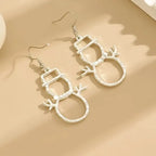 silver snowman earrings flat on beige surface showing outline design and hooks