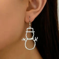silver snowman earrings hanging from ear with minimalist winter holiday design