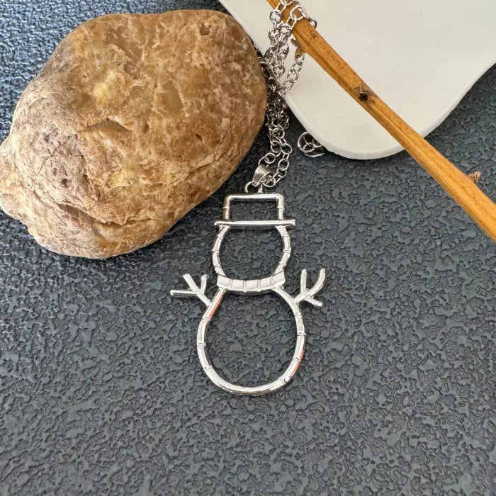 silver snowman earrings necklace pendant near rock showing shiny metal detail
