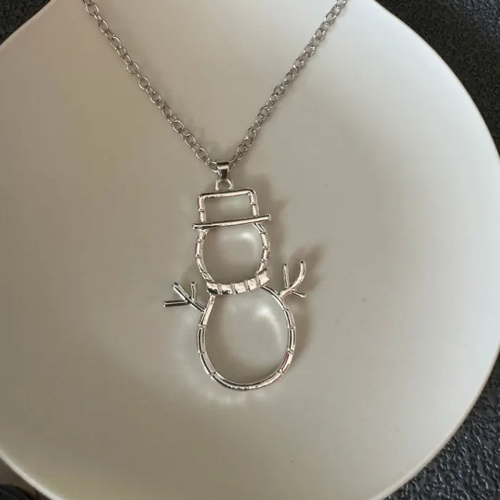 silver snowman earrings necklace pendant resting on plate highlighting winter charm