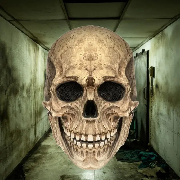 Frontal view of skull mask with deep eye sockets in dimly lit, grungy hallway.