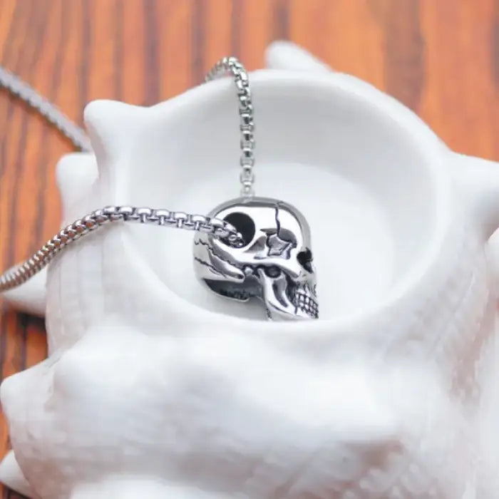 Skull pendant necklace creatively placed in a white seashell bowl for a unique presentation.