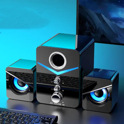 Stylish black computer speakers with blue LED lighting, subwoofer, and control panel on blue background