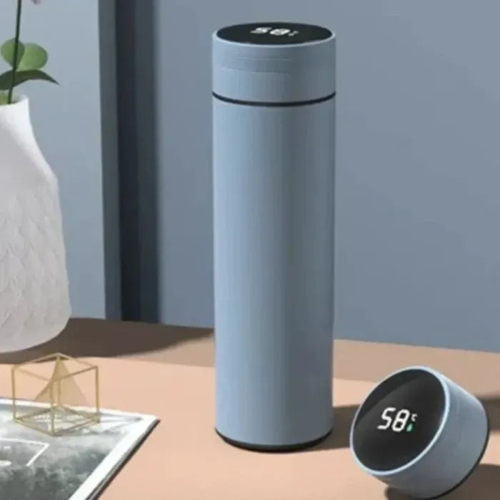 Sleek blue thermos bottle with digital temperature display, alongside small circular device on wooden surface