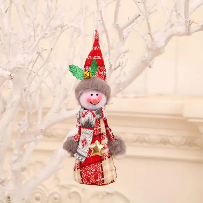 Smiling snowman gnome ornament with red plaid outfit, pointy hat, and golden star detail on white tree branch