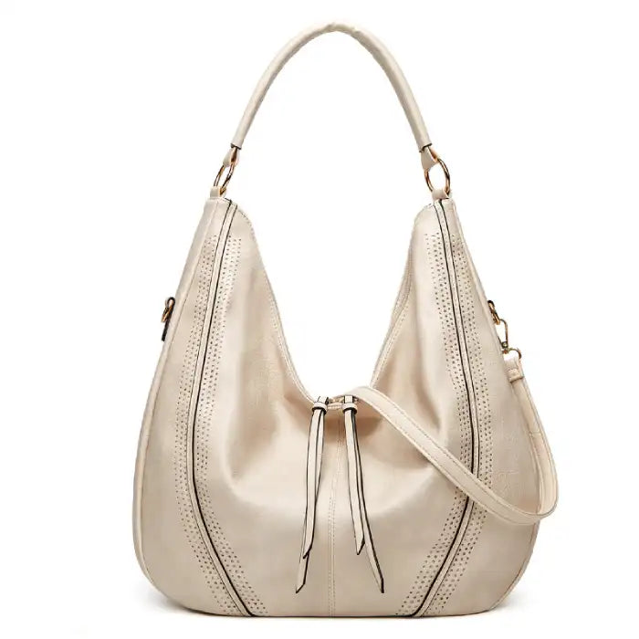 Soft leather hobo bag with perforated detail in cream, closeup showing drawstring closure and leather texture.