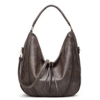 Soft leather hobo bag with perforated detail in gray, closeup showing slouchy crescent shape and drawstring.