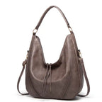 Soft leather hobo bag with perforated detail in gray, side view displaying shoulder strap and crescent silhouette.