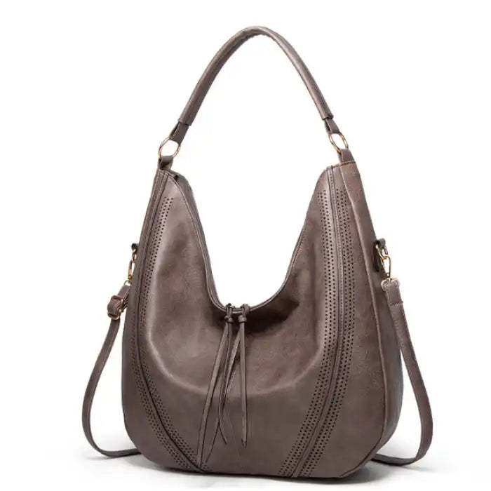 Soft leather hobo bag with perforated detail in gray, side view displaying shoulder strap and crescent silhouette.