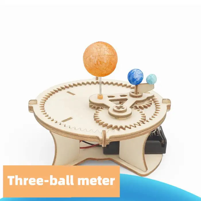 Solar system gear model with three colorful balls simulating planets in motion on wooden base