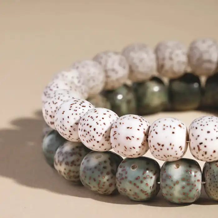 Closeup of speckled ceramic bead bracelet with elephant charm, showing white and green beads in detailed view.