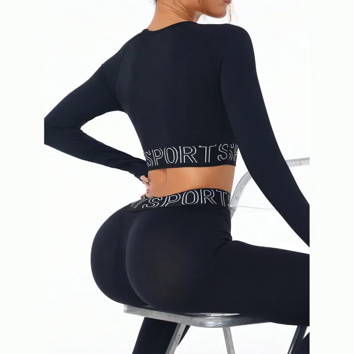 Black fitness set with sports text detail shown from back view while model sits on clear chair, highlighting seamless design