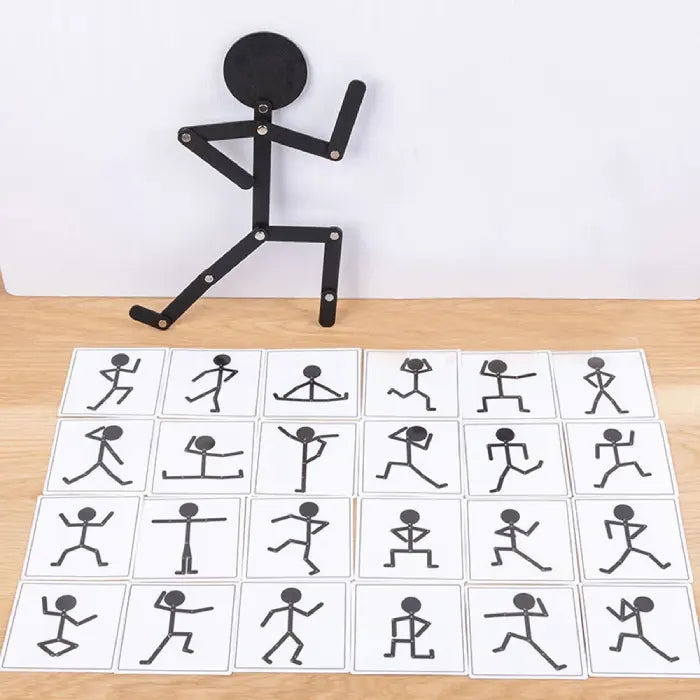 Black stick figure toy posed with 24 activity cards featuring various exercise and movement illustrations on a wooden surface.