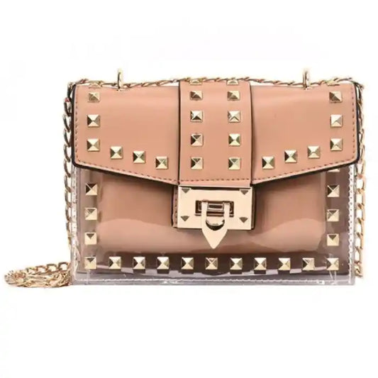 Pink leather crossbody bag with gold studs and transparent panels, featuring a chain strap and lock closure