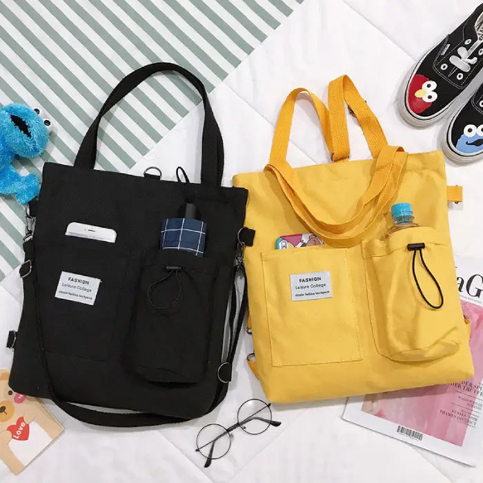 Canvas tote bags in black and yellow with multiple pockets, water bottle holder, and fashion label