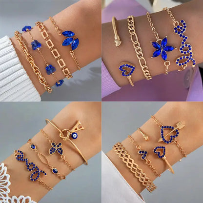 Display of multiple gold bracelet sets with blue gemstones in heart, floral, and geometric patterns.