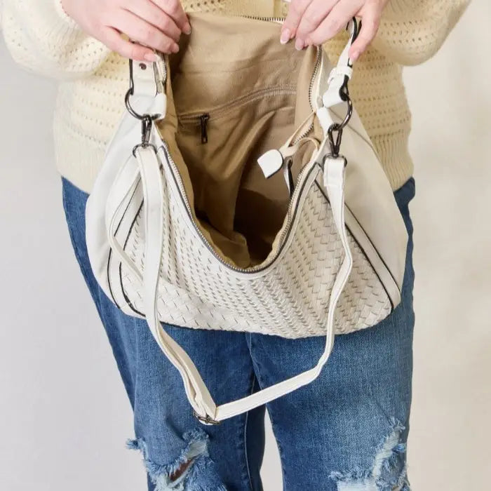  Close-up of an open white woven handbag showcasing its spacious interior.