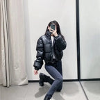 Stylish puffer jacket in black worn by model with jeans and boots in mirror selfie
