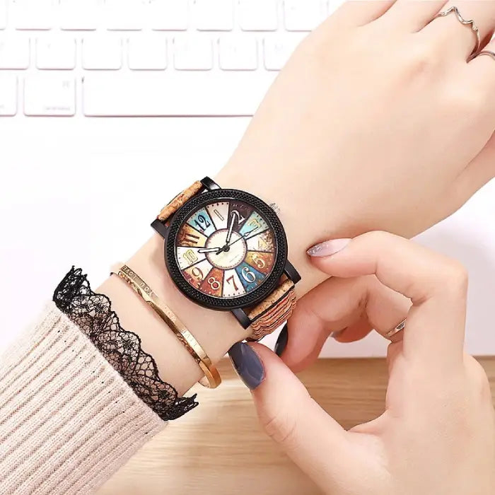 Stylish analog wristwatch with a cork strap and colorful dial worn on a woman's wrist for modern style.