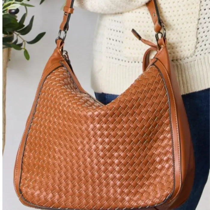 Close-up of stylish brown woven leather handbag on shoulder.