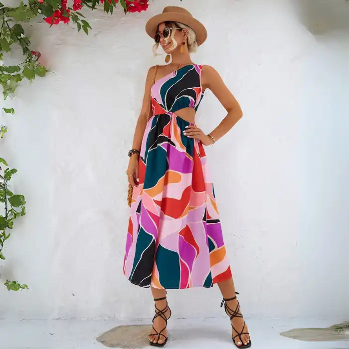 Summer dress with one shoulder design featuring vibrant colorful abstract pattern, styled with straw hat and woven bag for vacation wear