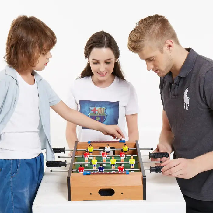 Family playing tabletop foosball game together with focus on interaction and team play.