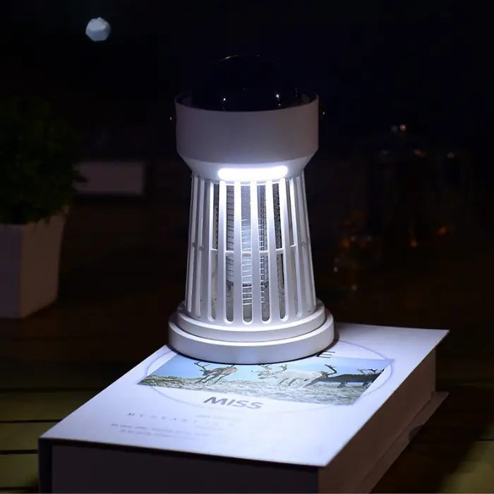 tabletop mosquito trap emitting light, placed on a book for nighttime use.