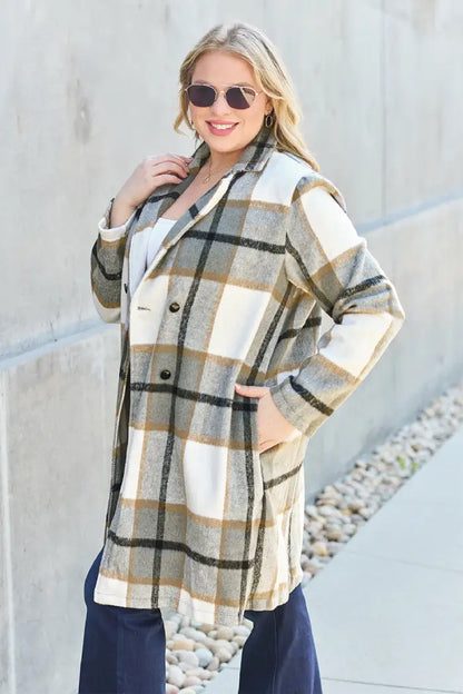 Side view of a woman wearing a tan and white plaid wool coat styled with dark jeans and a white top in an outdoor walkway.