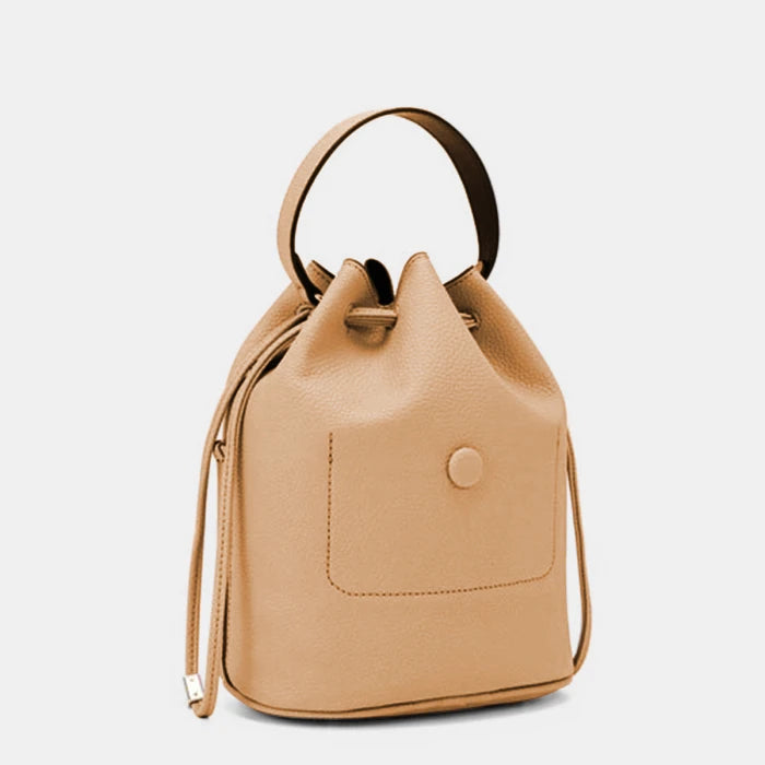 Side profile of structured leather handbag featuring external pocket detail and top handle design