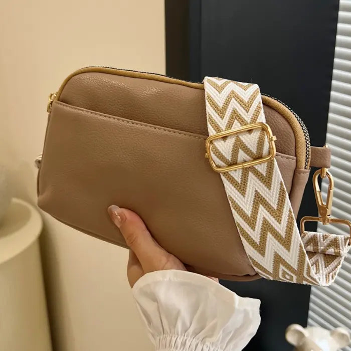 Taupe crossbody bag with neutral chevron strap, a versatile choice for casual and chic looks.