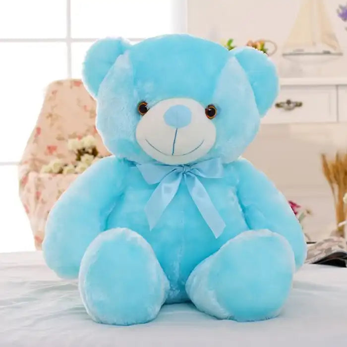 Teddy Bear blue plush toy with ribbon sitting on a bed