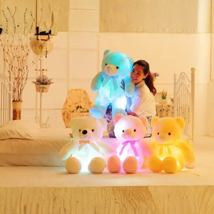 Teddy Bear glowing plush toys in multiple colors beside a smiling woman.