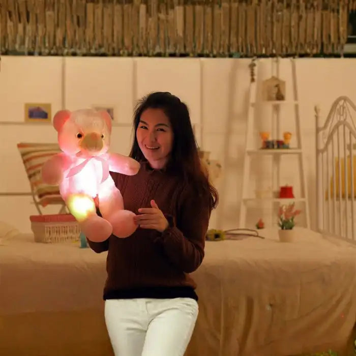 Teddy Bear glowing pink plush held by a woman in a cozy room.