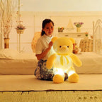 Teddy Bear glowing yellow plush displayed with a woman sitting beside it.