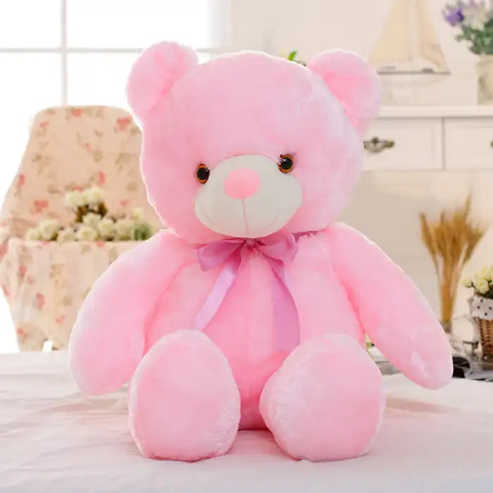 Teddy Bear pink plush toy with ribbon sitting indoors.