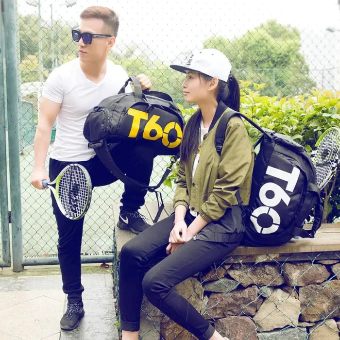 Two young tennis players, male and female, standing by fence with sports bags and rackets, dressed in casual athletic wear