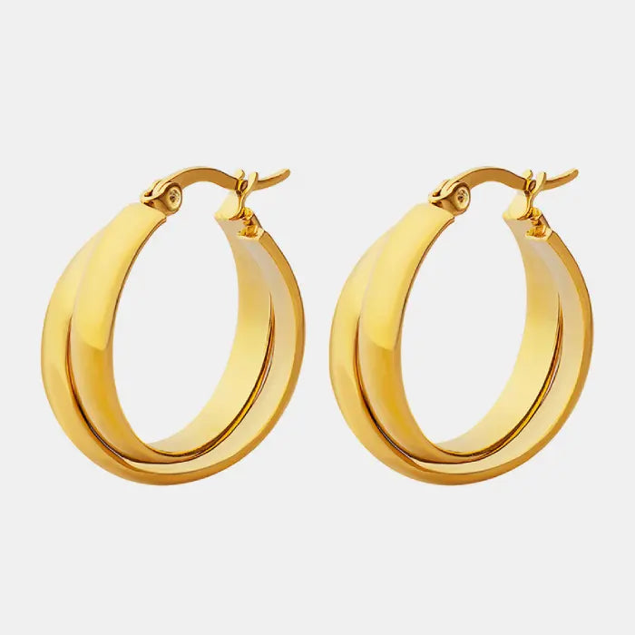 Pair of chunky golden hoop earrings with wide curved band and secure clasp closure